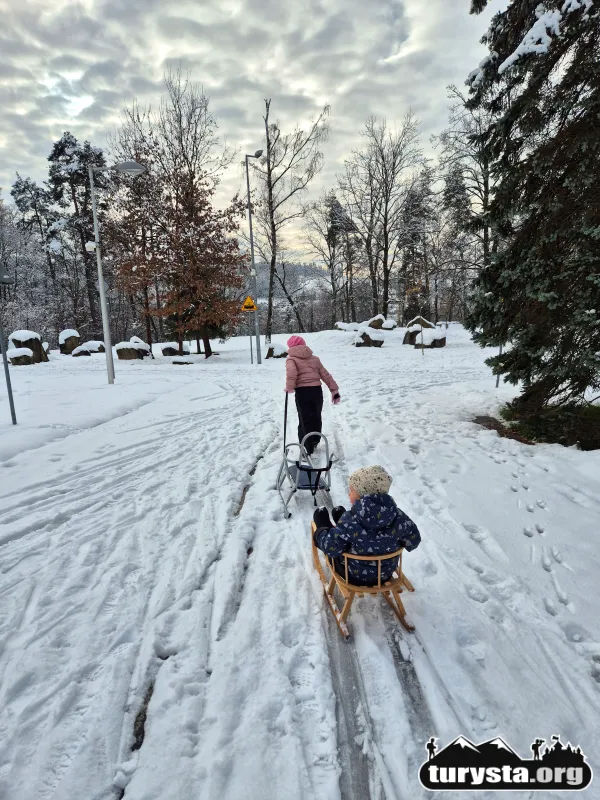 Dziecko ciągnące dziecko na sankach po wyślizganej trasie w Miasteczku Rowerowym w Rabce-Zdroju.