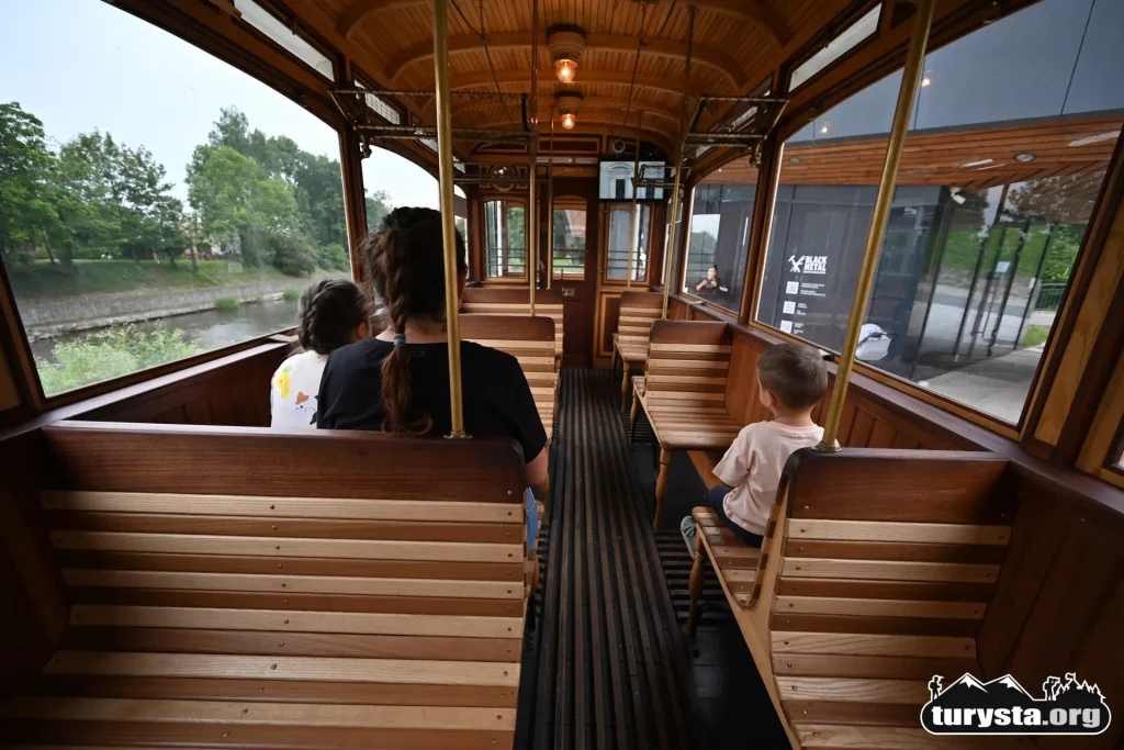 Drewniane ławki i historyczne wnętrze repliki zabytkowego tramwaju w Cieszynie.
