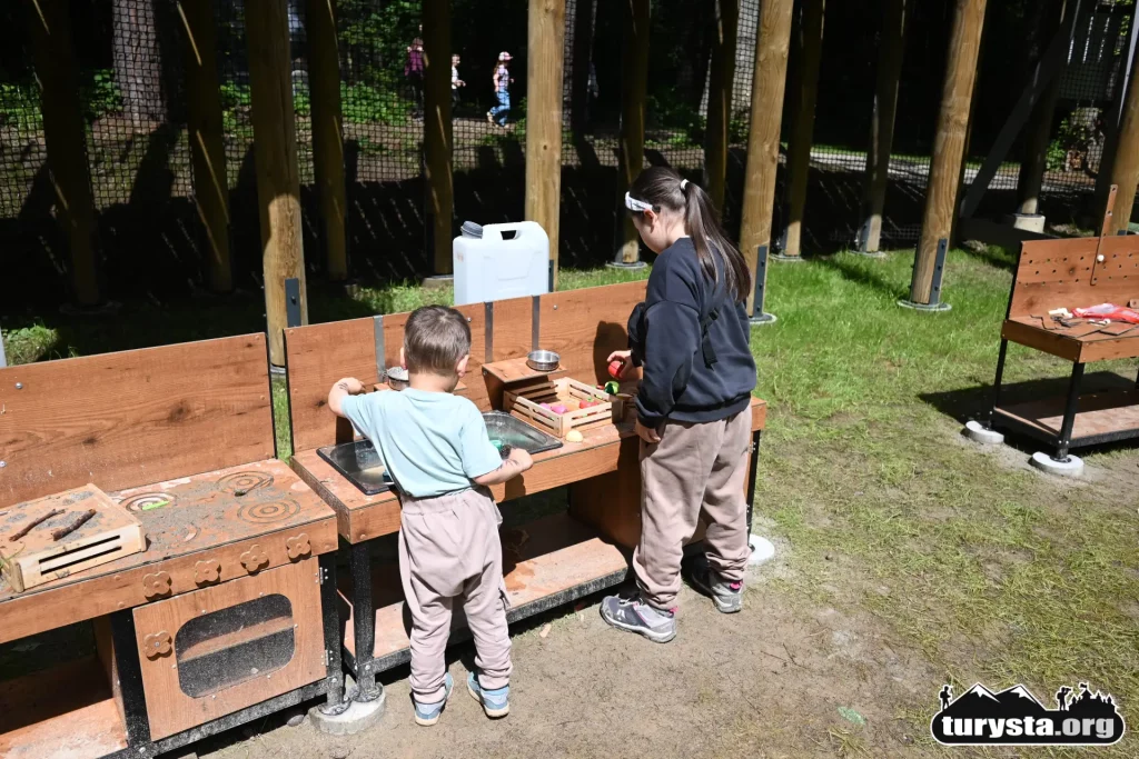 Dzieci bawiące się przy drewnianym stole edukacyjnym w strefie sensorycznej Orbisfery