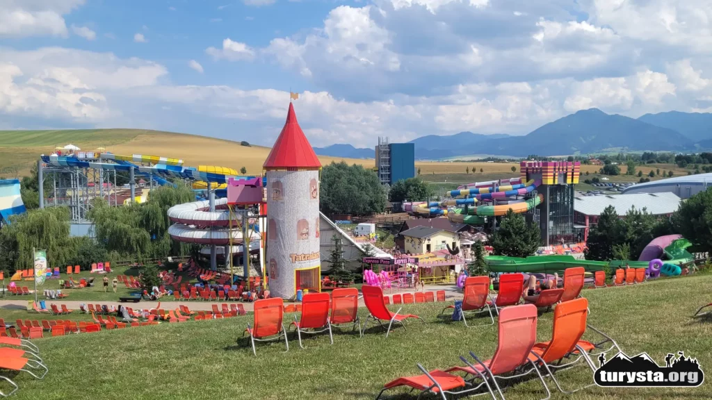 Strefa relaksu z leżakami w Tatralandii z widokiem na góry i zamek dla dzieci.