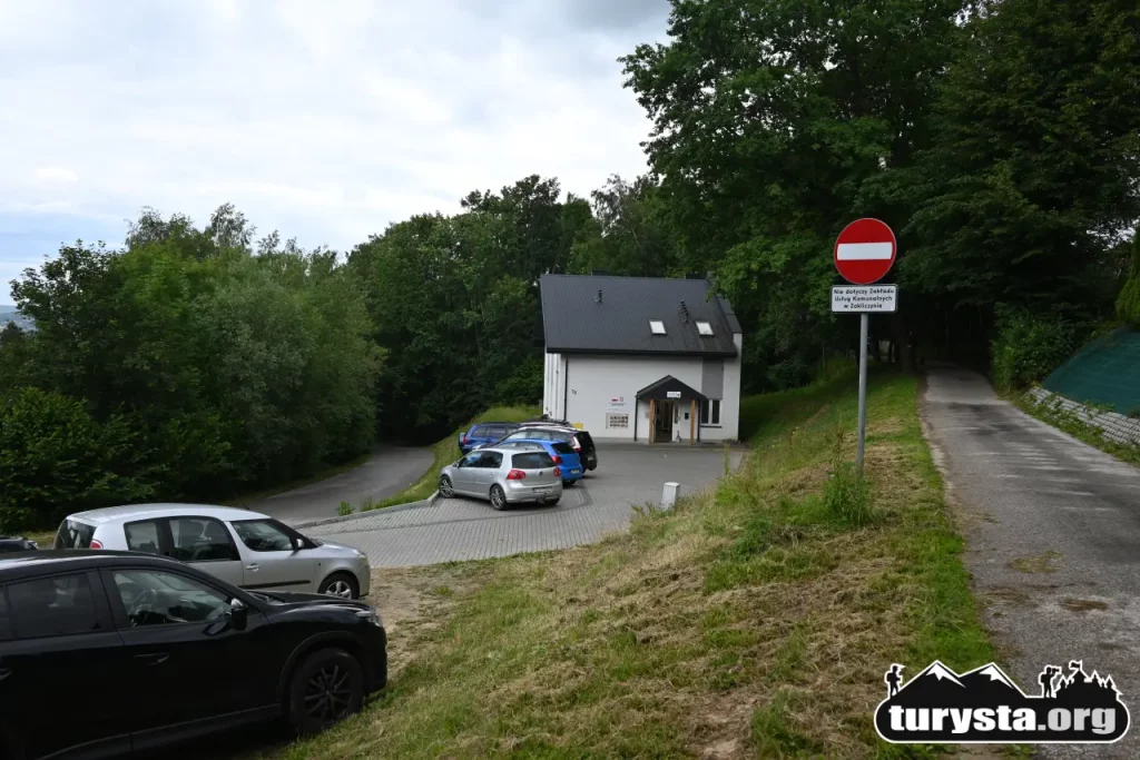 Samochody zaparkowane na bezpłatnym placu przy budynku Świetlicy w Melsztynie u podnóża góry zamkowej.