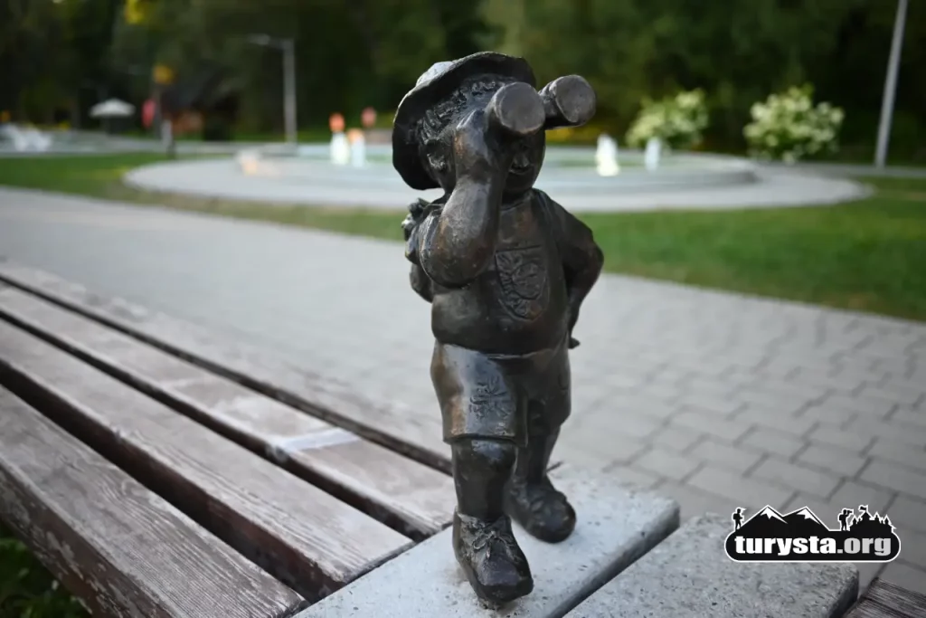 Figurka Rabcia Wędrowca z lornetką na ławce przy Bulwarach nad Poniczanką w Rabce-Zdroju