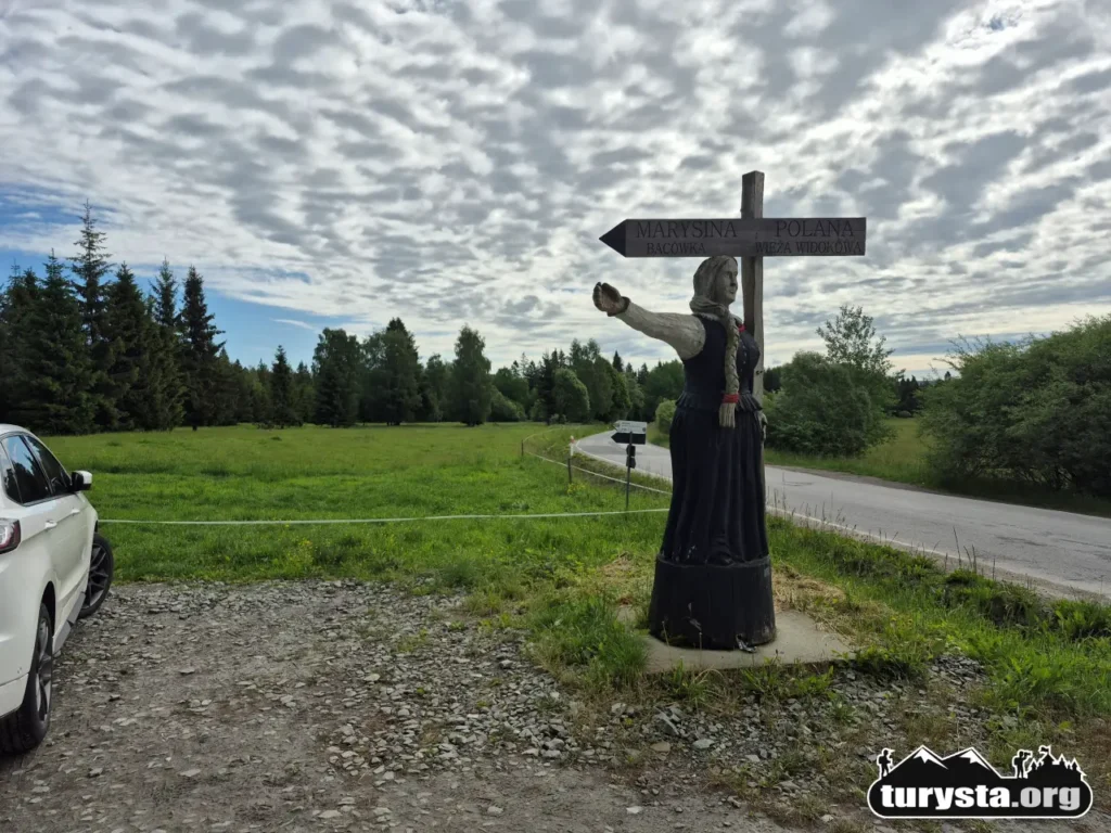 Nieduży darmowy parking przy głównej drodze z drewnianą rzeźbą – początek trasy na Marysiną Polanę na Orawie.