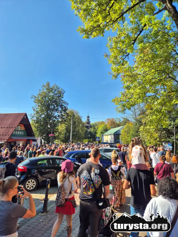 Rodziny z dziećmi stojące przy trasie pochodu owiec w słoneczny dzień w Rabce